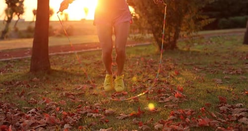 Happy woman jump rope outdoors in autumn park