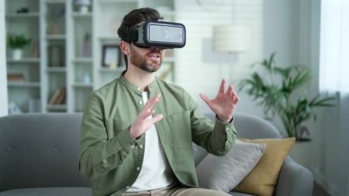 Handsome man using VR glasses for video call and chatting in virtual reality simulator sitting
