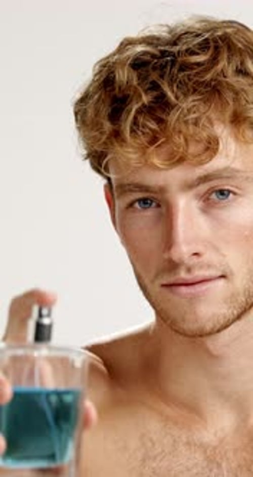 Face, happy man and spray perfume in studio for fragrance, hygiene and fresh scent