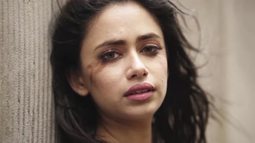 Close up headshot of a young indian female with smudged make up sad by the wall slowmotion