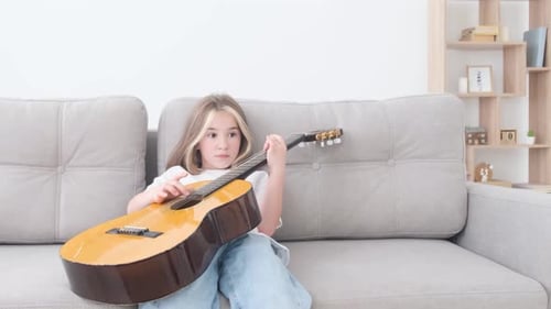 Girl Plays Guitar on Couch in Living Room