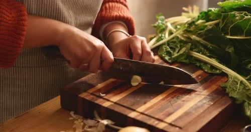 Hands Dicing Garlic on Wooden Cutting Board