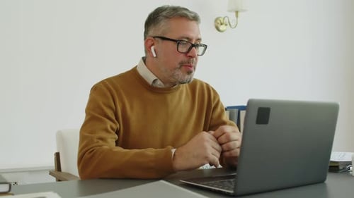 Man Attending Video Conference on Laptop at Home