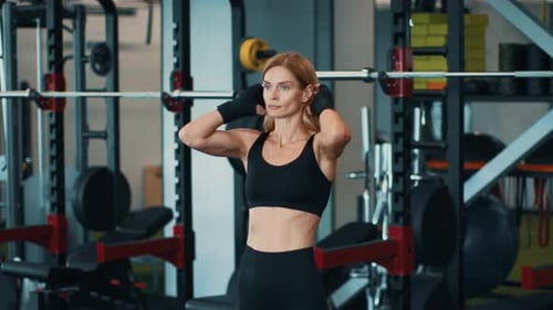 Woman Preparing for Weight Training in a Gym With Fitness Equipment Around
