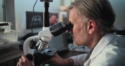 Scientist Looking Through Microscope in Bright Laboratory