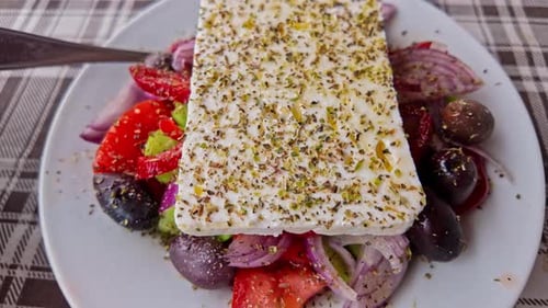 Gros plan de la salade grecque avec du fromage feta garni d'herbes sur une nappe à carreaux