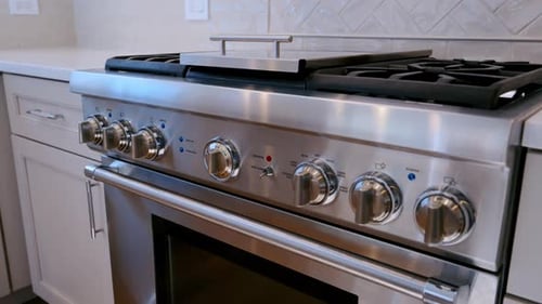 Stainless Steel Gas Stove with Control Knobs in a Modern Residential Kitchen Close View of Cooking