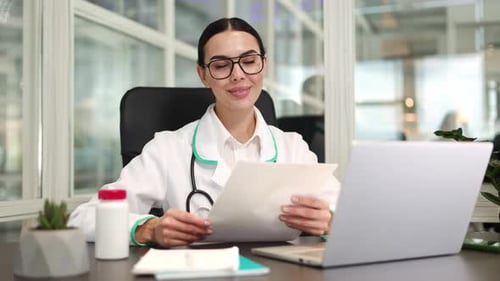 Female Doctor Sitting and Smiling While Holding Medical Document Outdoor