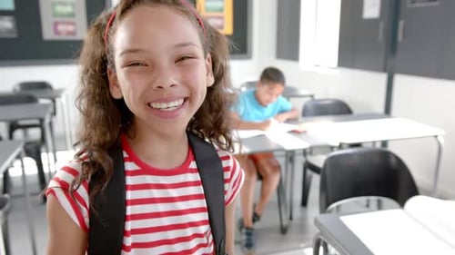 Smiling Schoolgirl with Backpack in Classroom
