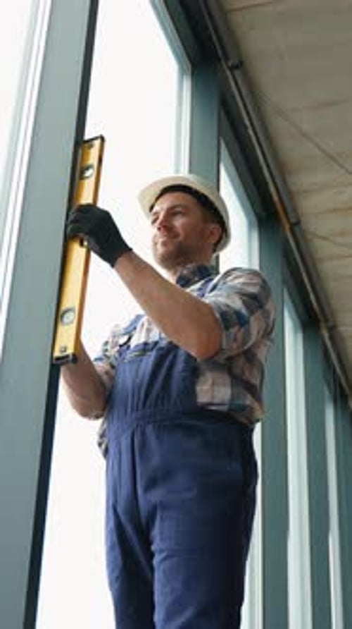 Construction Worker Checking Window Alignment with Level