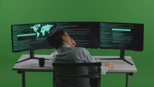 Tired Asian Man Developer Yawning While Write Code With Multiple Computer Screens In Green Screen