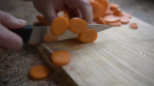 Hands Slicing Carrots on Wooden Cutting Board