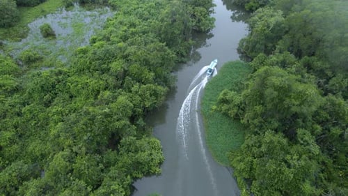 tilt up camera movement with view of a boat sailing through a river heading towards the mountains at