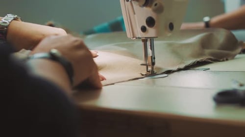 Close up of fashion designer hands stitching cloth using sewing machine