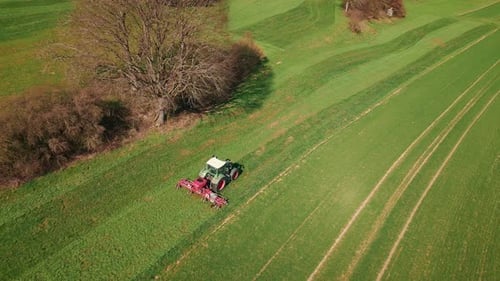 Combine agriculture machine working on green field. Tractor cultivating meadow