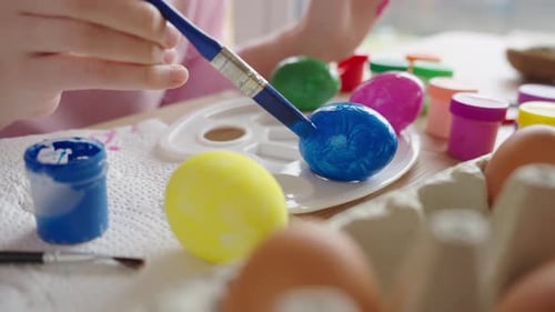 Woman painting Easter eggs at home for spring holiday