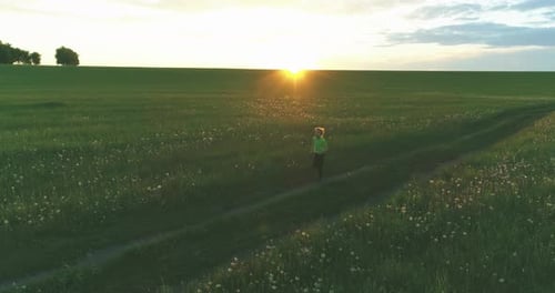 Sporty Child Runs Through a Green Wheat Field Evening Sport Training Exercises at Rural Meadow A