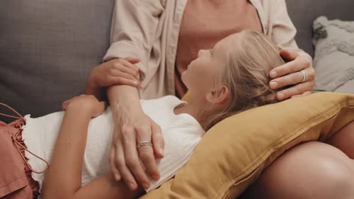 Girl Resting on Lap of Adult on Couch