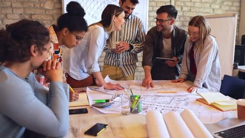 Group of young business people discussing architectural designs in office.