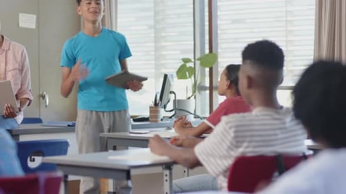 Presenting project, student holding tablet and speaking to classmates in school