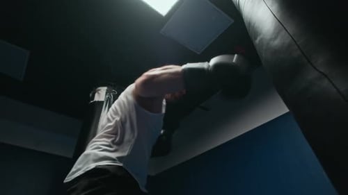 Muscular Man Punching Heavy Bag in Gym