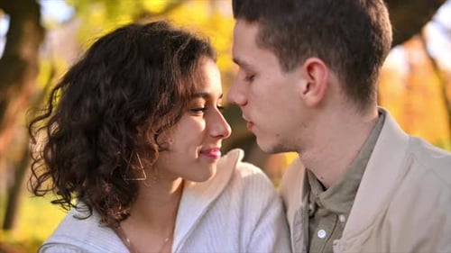 A romantic couple in an autumn park. Man kissing his woman. Autumn atmosphere, yellowed trees and le