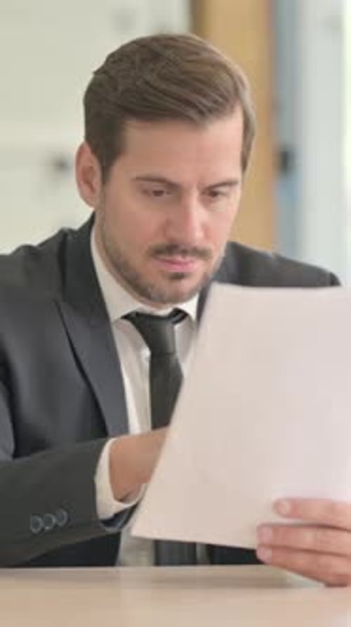 Excited Businessman Looking at Document in Office
