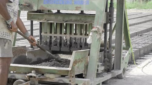 Man operating brick-making machine in rural area