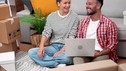 Couple Using Laptop in New Home after Moving