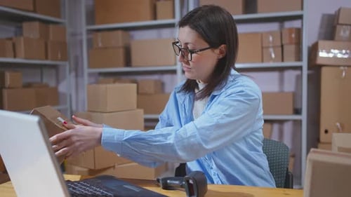 A Young Female Warehouse Worker Uses a Barcode Scanner in Her Work Close Up