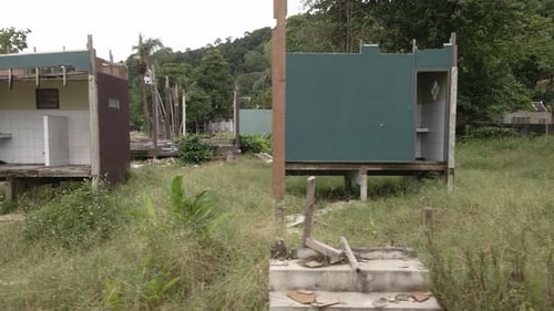 Left moving trucking shot of an abandoned derelict destroyed bungalows , beach resort in Thailand ,f