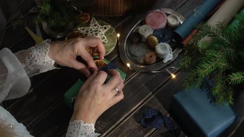 Hands Decorating Christmas Gift With Orange Slice