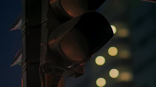 Traffic Light Against the Background of the Evening City Flashes Green and Changes to Orange