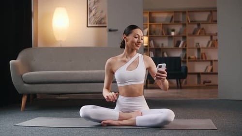 Woman in Workout Clothes Using Phone on Yoga Mat