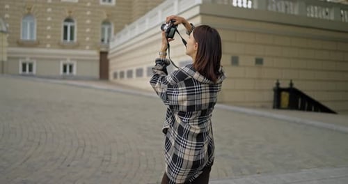 Woman Photographs Building with Vintage Camera in City