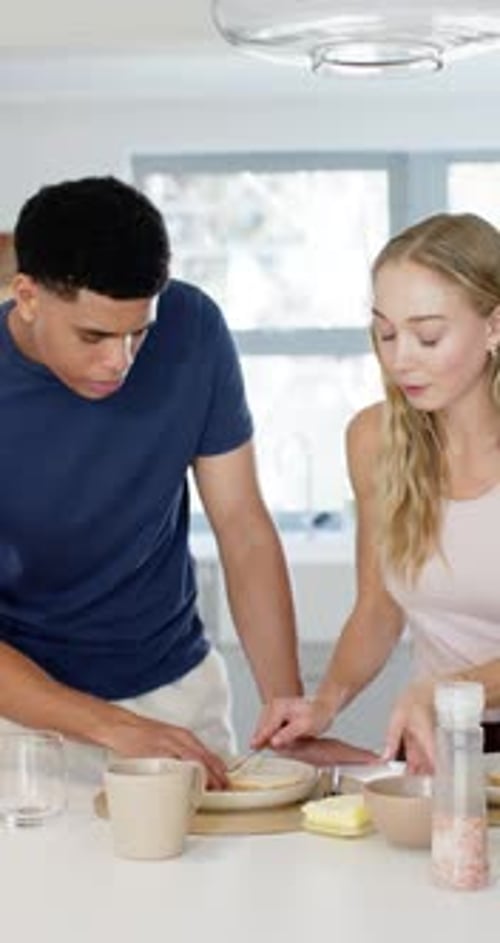 Vidéo verticale : couple diversifié arrangeant des assiettes dans la cuisine, étalant les aliments avec une cuillère pour servir