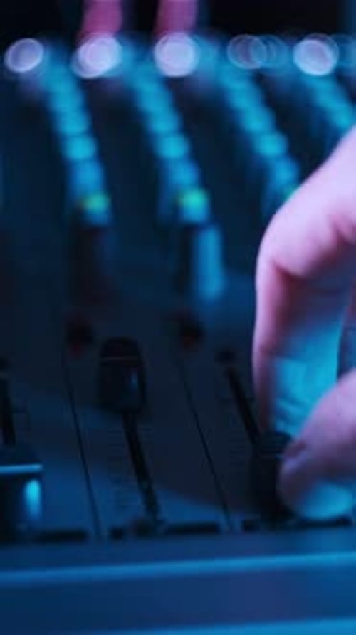 Vertical Sound Engineer Moves Faders Up and Down on Audio Mixer in Neon Light