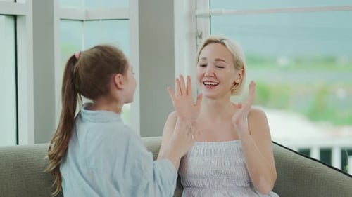 Caucasian mother and little daughter smiling while playing clapping hands game at home