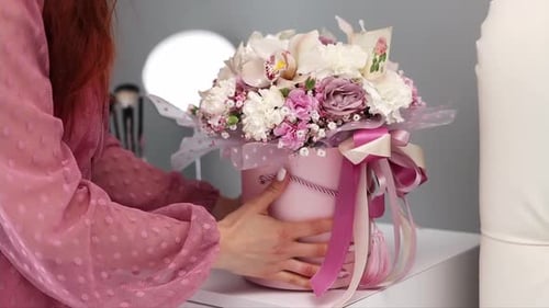 Woman Adjusts Ribbon on Pink Floral Gift