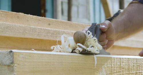 Carpenter using hand plane to smooth rough wood