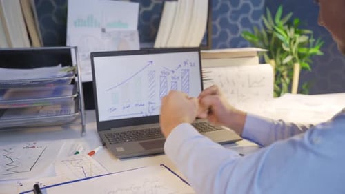 Adult At Desk With Laptop And Charts