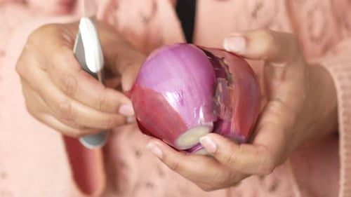 Hands Peeling a Red Onion with Knife