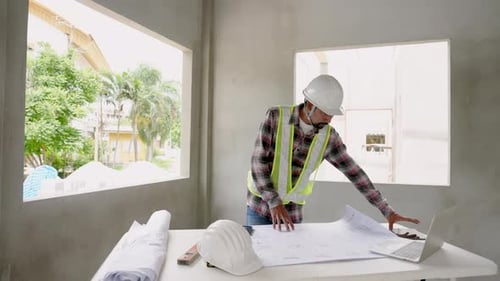 Man of multiethnic Wear green reflective vest and safety helmet on house under construction. Indian