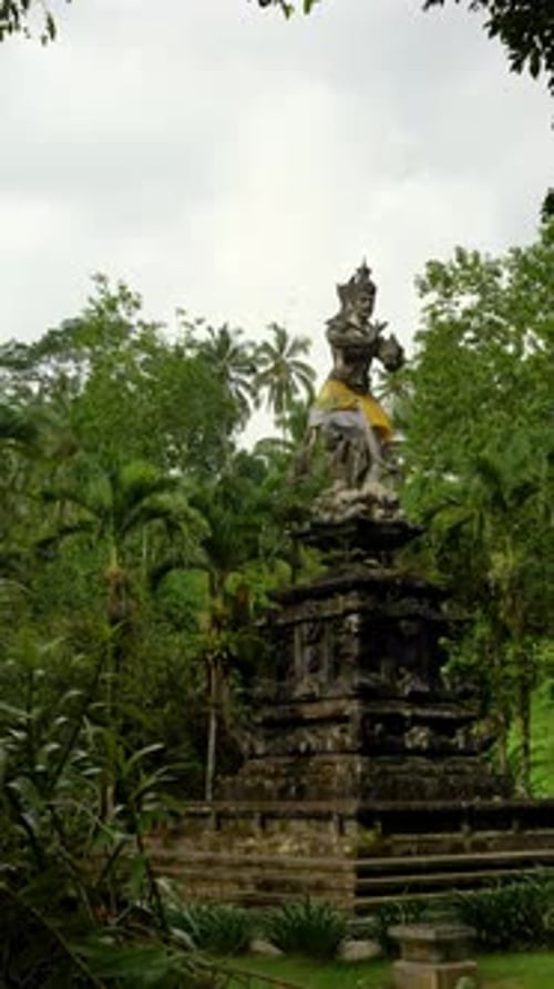 Sculpture en pierre sacrée debout dans un cadre luxuriant de jardins de temples tropicaux