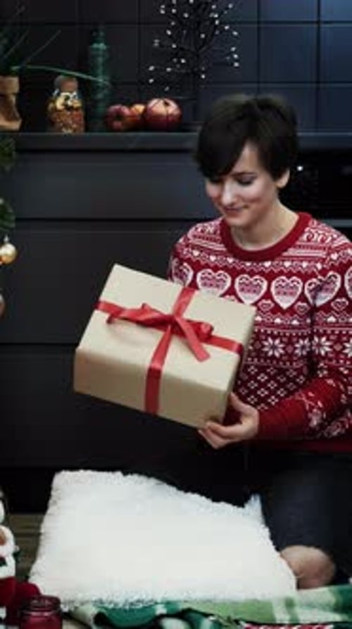 Woman wrapping present in front of Christmas tree