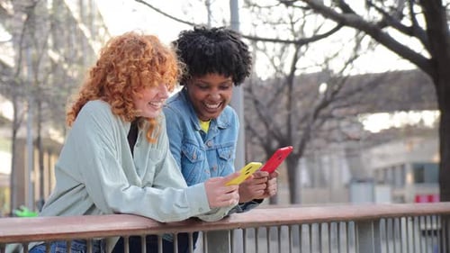 Smiling friends looking at smartphone in urban setting