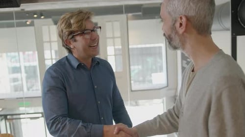 Businessman Greeting Senior Coworker with Handshake in Office