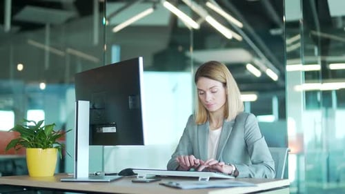 Büroangestellte im Anzug arbeitet am Computer-PC vor dem Bildschirm, Korrespondenz, sitzt