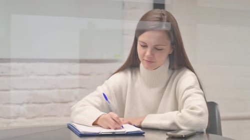 Young Adult Woman Writing on Paper at Desk