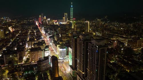 Aerial hyperlapse shot of lighting cityscape at night with traffic on road and skyline in background